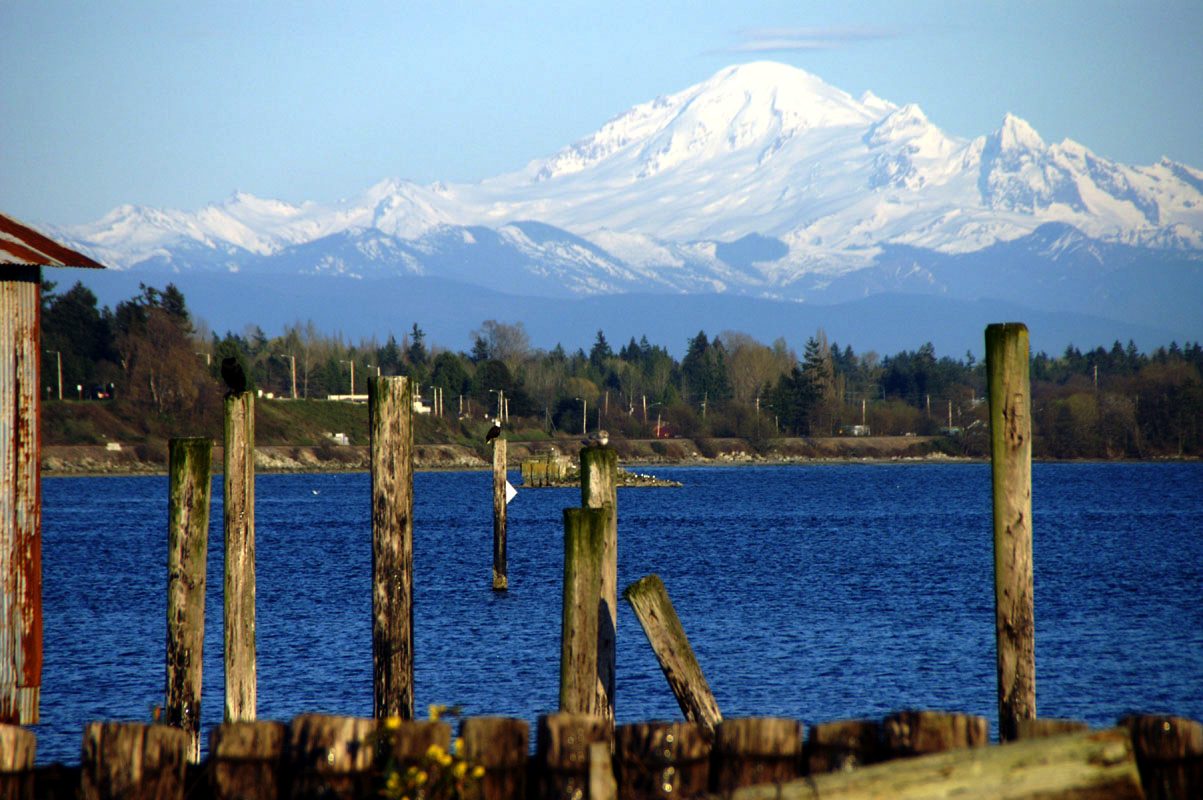 One of the best beaches in Whatcom County, Semiahmoo! Snowy Mount Baker viewed from Semiahmoo Park, with the ocean and wood piers in the foreground.