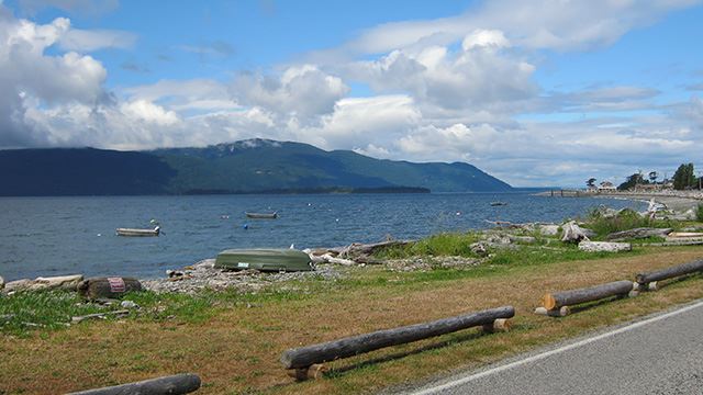 A landscape with a beach, Lummi Bay, a mountainous island and clouds in the background.