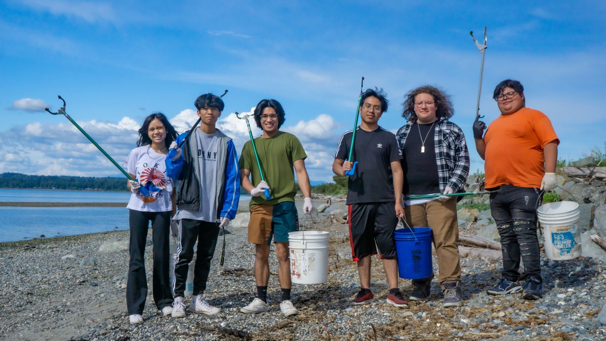 A group of young people with trash grabbers standing on the beach along Semiahmoo Spit